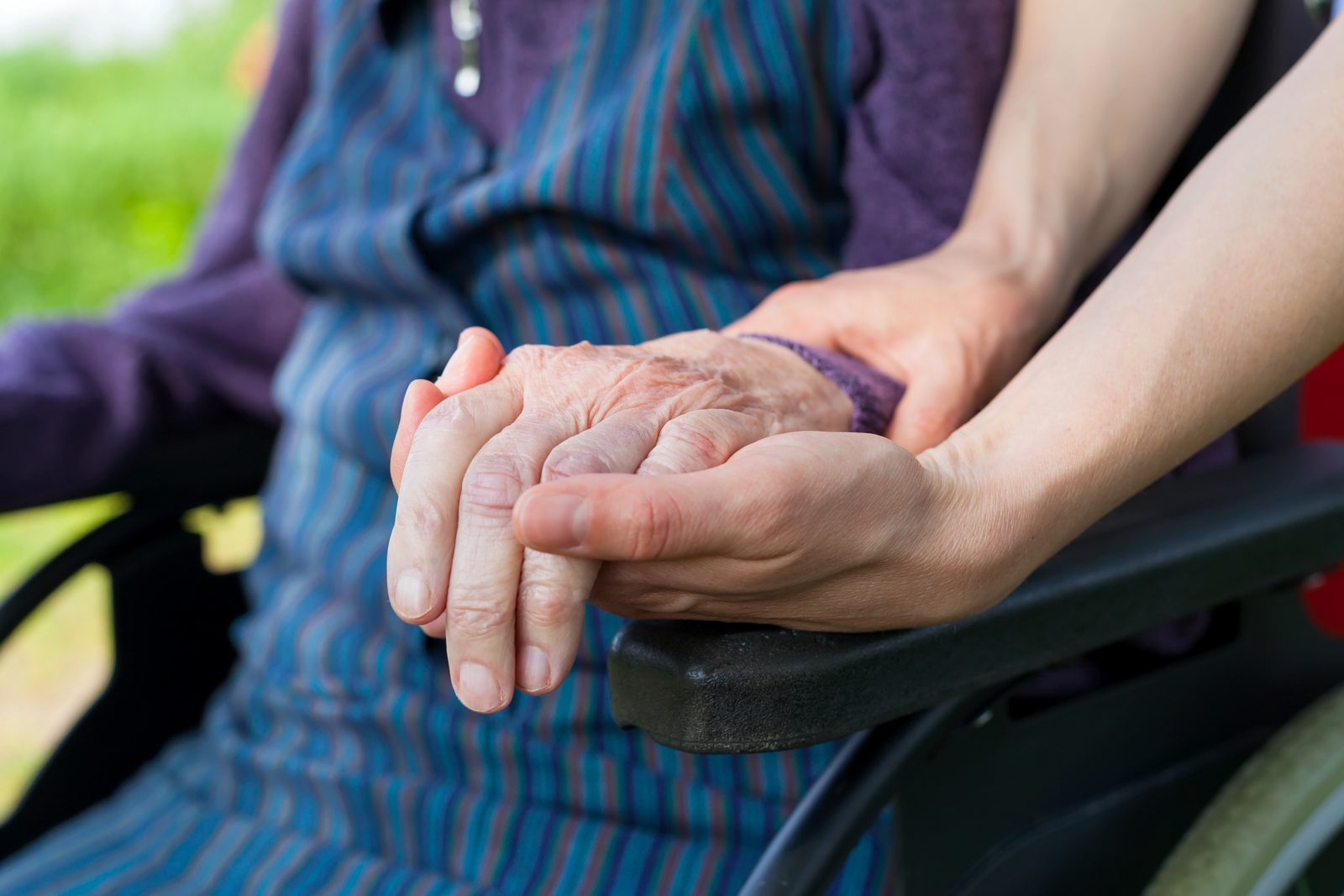 A caregiver holding an elderly person's hand